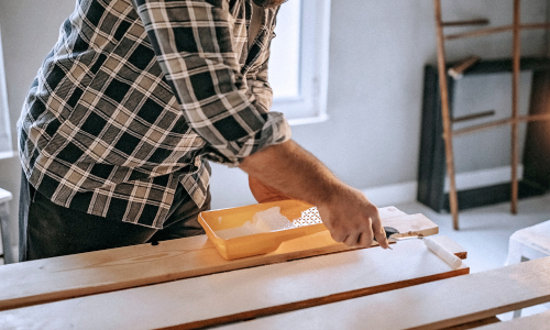 Man painting wood indoors